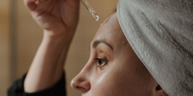 Woman applying Obagi Medical Skincare serum to her face (model)
