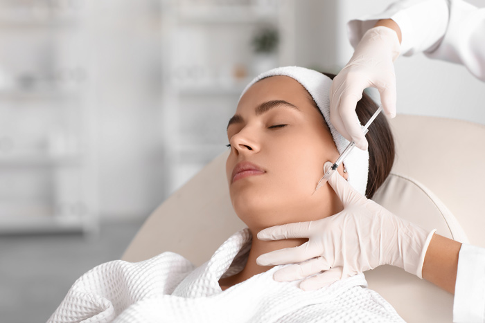 Provider administering an injectable treatment along the jawline during a facial rejuvenation procedure.